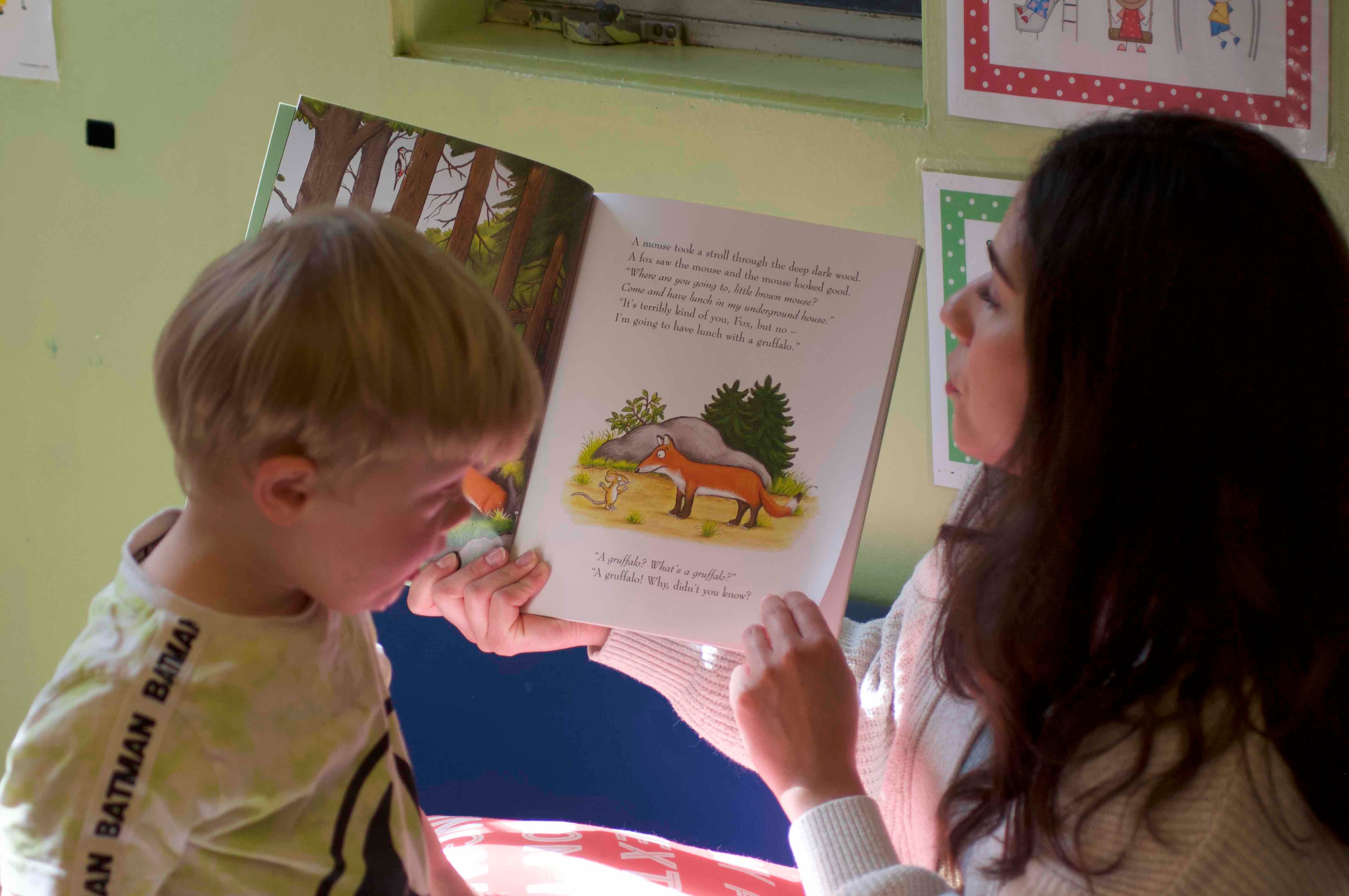 Teacher reading "The Gruffalo" to preschooler during storytime at Kids Konnect San Mateo
