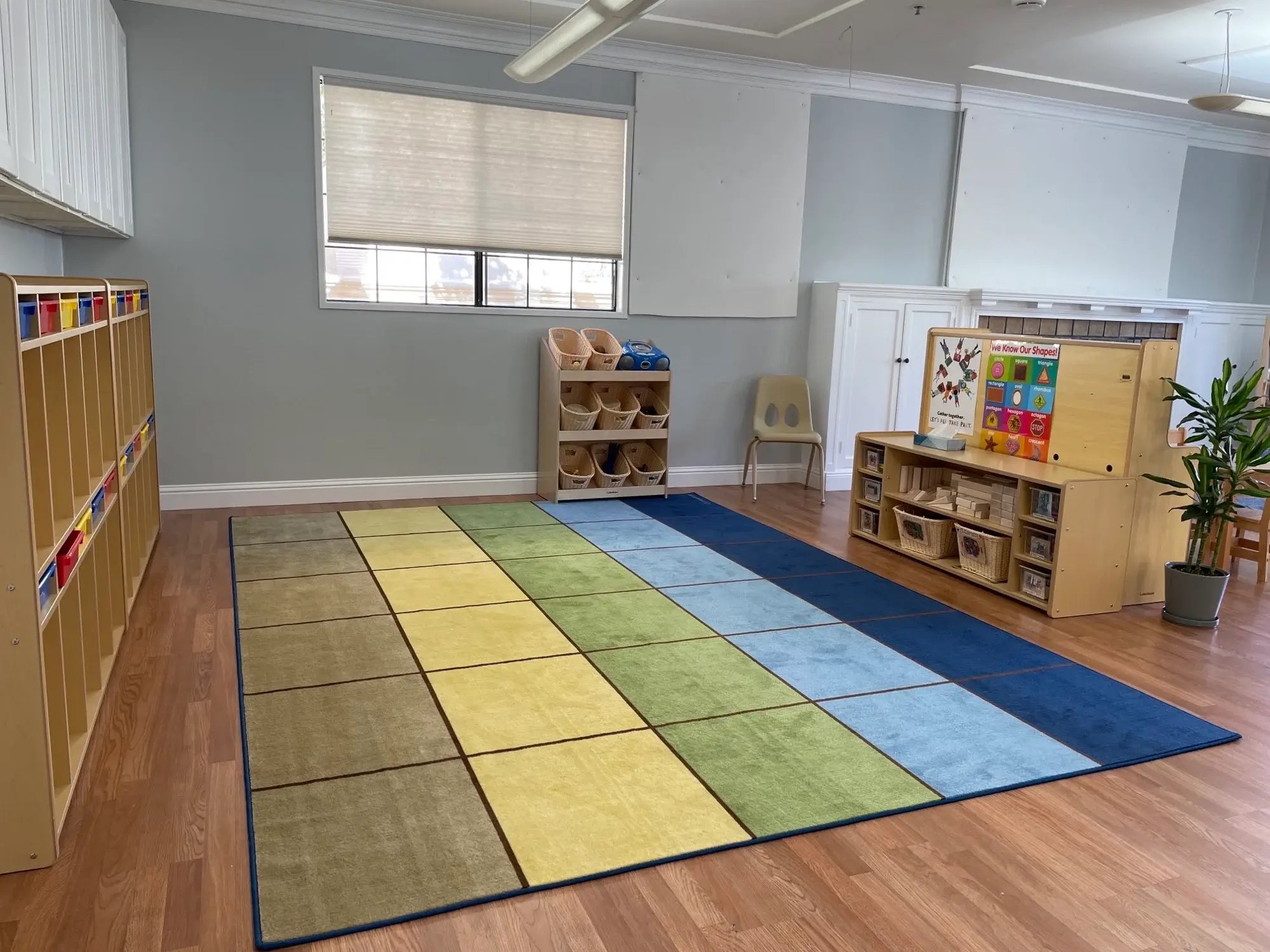 Organized preschool classroom with colorful rug and learning centers at Kids Konnect