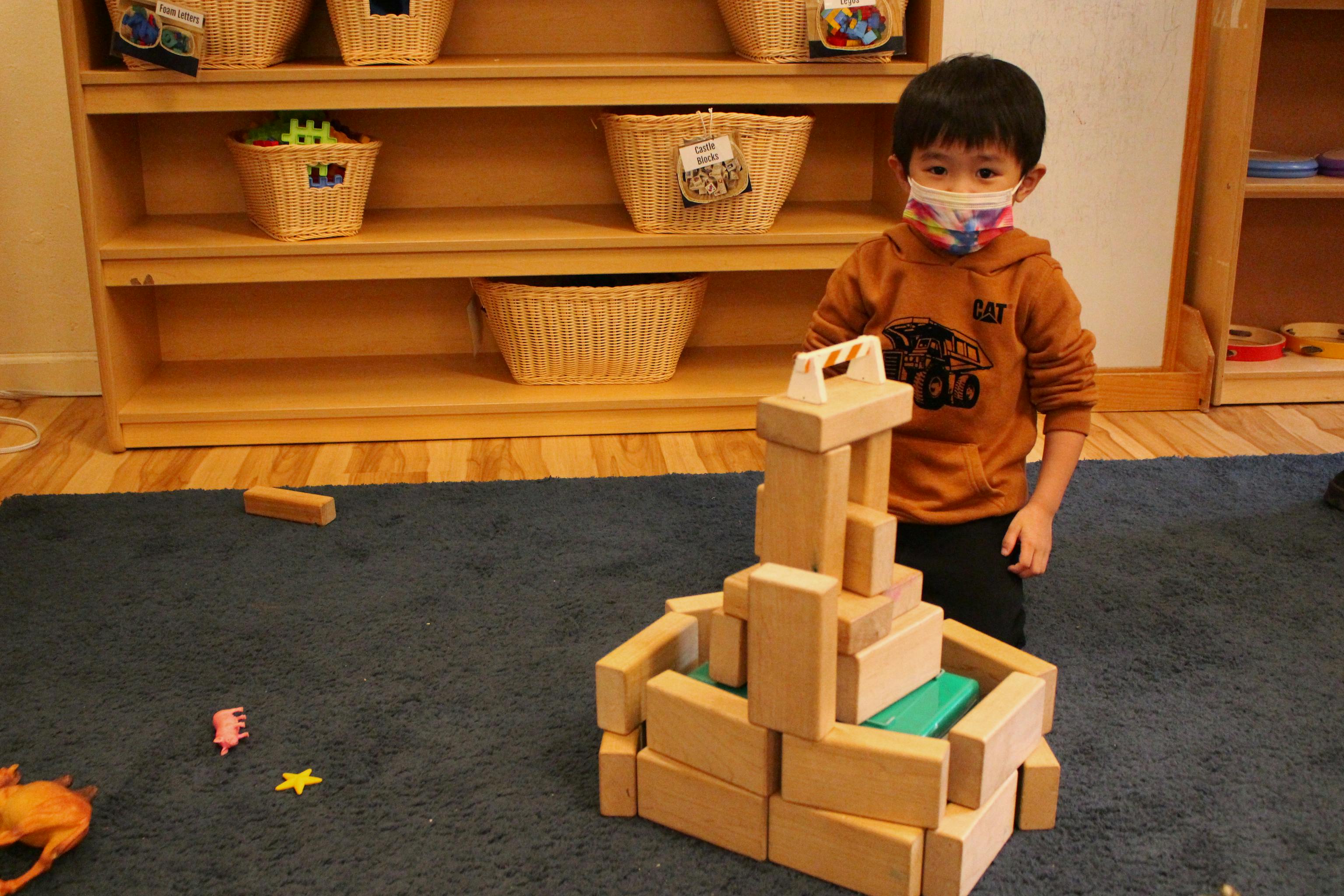 Preschool boy constructing a tall block tower in the classroom at Kids Konnect