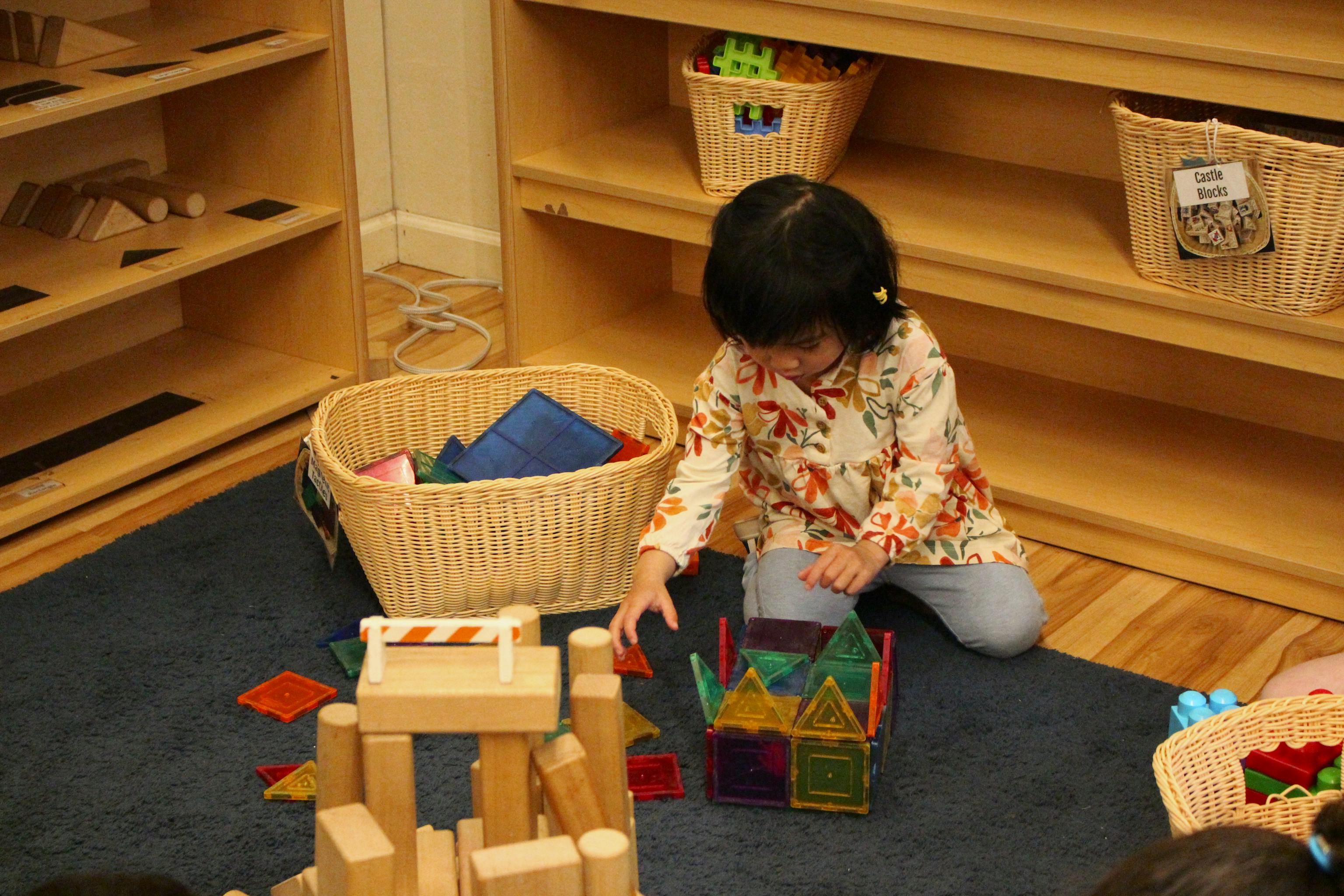 Preschool girl building structures with magnetic tiles and manipulatives at Kids Konnect