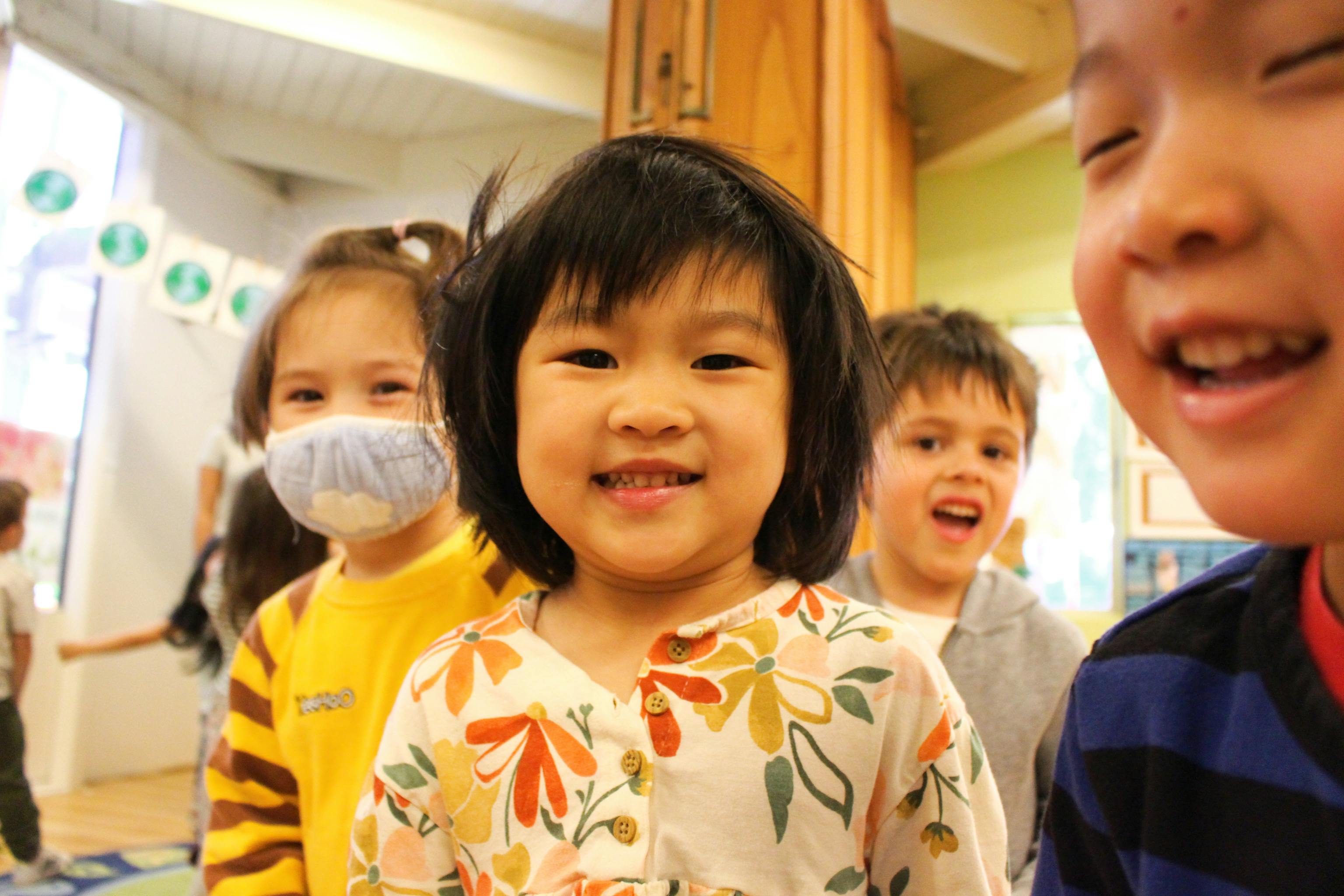 Preschool children smiling and walking together inside Kids Konnect San Mateo school hallway