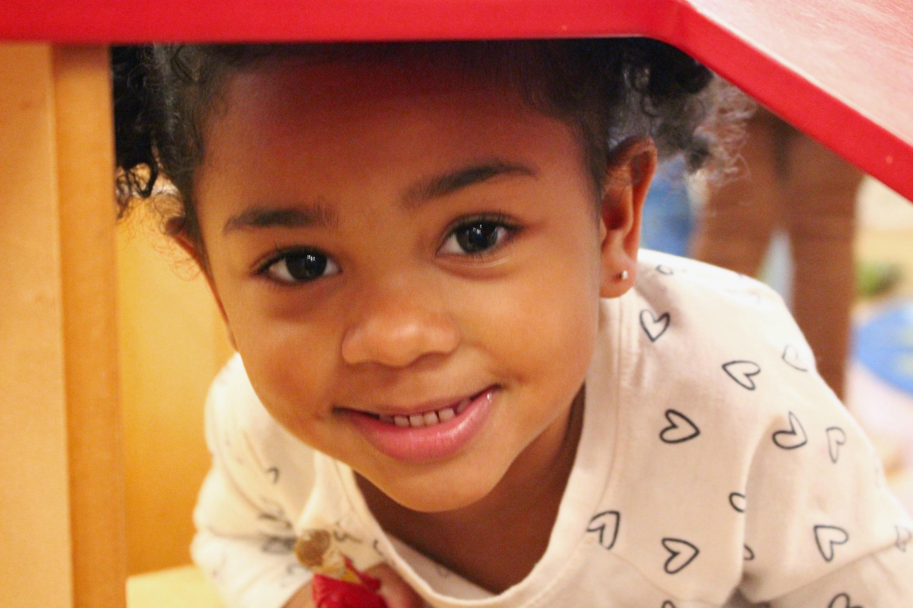 Smiling preschool girl in tunnel play structure at Kids Konnect outdoor playground