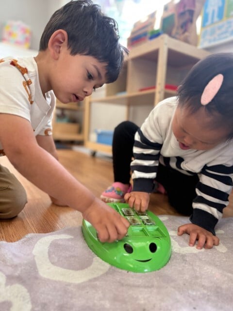 Two toddlers working together on a puzzle for fine motor development at Kids Konnect