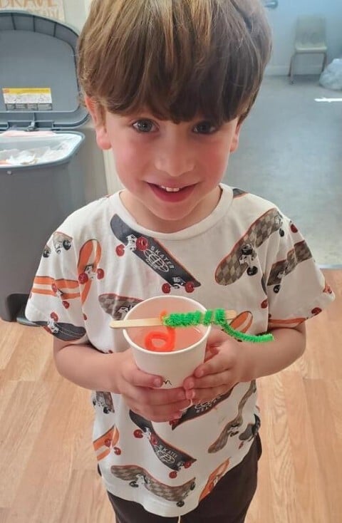 Preschooler smiling while holding a bug-themed STEAM craft at Kids Konnect