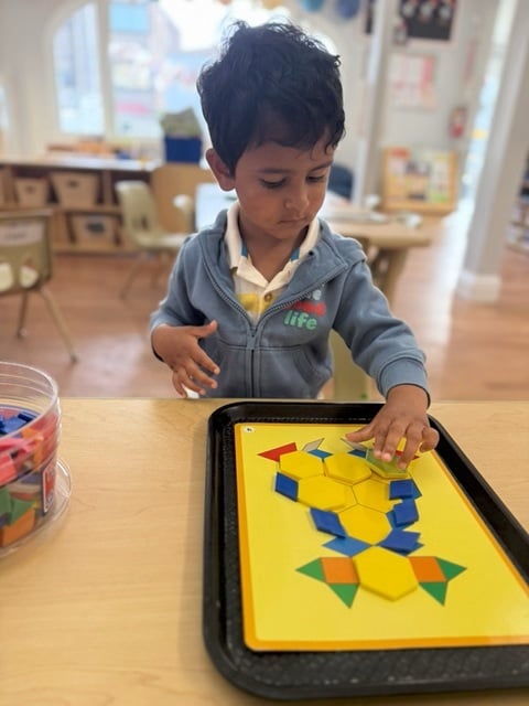 Preschooler working on geometric shape patterns during STEAM center activity