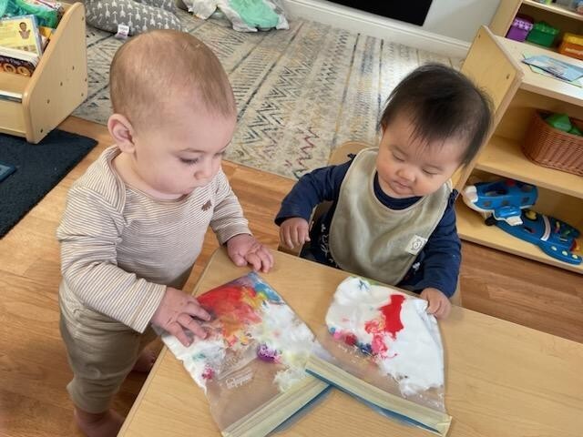 Infants exploring colors through collaborative painting at Kids Konnect